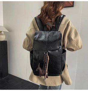 Close-up of black PU leather backpack with decorative charms on back of a model