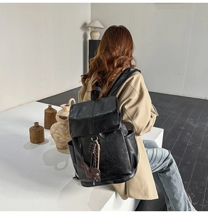 Chic black PU leather backpack detail with sausage dog charm shown on a model's back