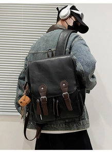 Detail eines schwarzen Lederrucksacks mit braunen Riemen auf dem Rücken des Modells