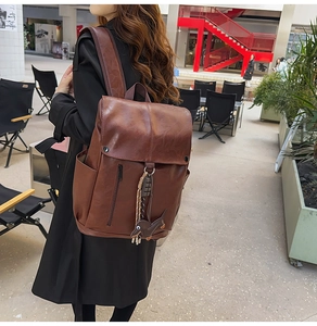 Brown retro leather backpack featuring a front vertical zip pocket and puppy charm