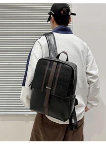 Rear view of minimalist black leather backpack with brown vertical straps on male model