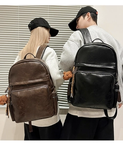 Detail view of large PU leather backpacks in brown and black with bear charms