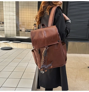 Detail of dark brown leather backpack featuring a cute dog charm and side pocket