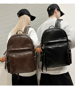 Detailed view of large PU leather backpacks in black and brown with bear charms
