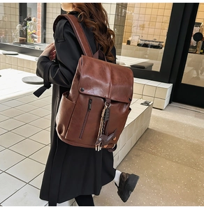 Detailed view of the brown vintage PU leather backpack with a decorative animal pendant