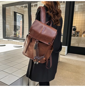 Detail of vintage brown leather backpack with cute dog charm and side pocket storage