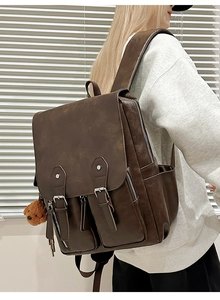 Detail eines dunkelbraunen Vintage PU-Rucksacks mit Vordertaschen und Plüschbär-Anhänger