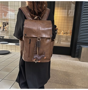 Brown PU leather backpack with flap closure and dachshund charm shown on a model