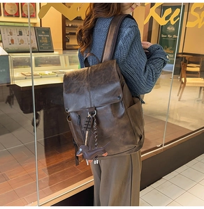 Detail view of brown vintage leather backpack with cute dog pendant and magnetic flap