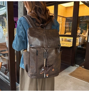 Detail of vintage brown leather backpack featuring a unique dachshund dog charm hanging