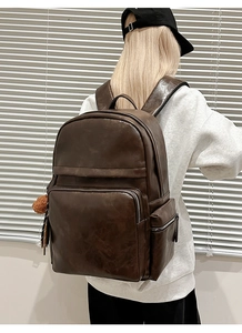 Close-up of dark brown PU leather backpack with vintage texture and stylish fur ball charm