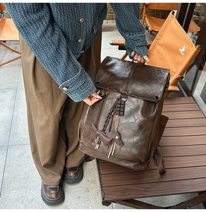 Detail of vintage dark brown leather backpack with retro charm and dachshund pendant
