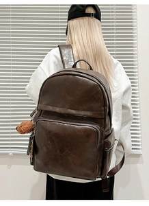 Detail of dark brown leather laptop backpack with textured finish and cute bear charm