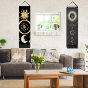Detail of sun and moon wall tapestries with tassels hanging on a white brick wall