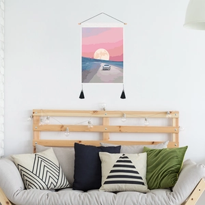 Pink sunset astronaut tapestry with tassels hanging over a sofa in a cozy living room