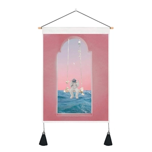 Detail of artistic pink astronaut tapestry with wooden hanging rod and black tassels