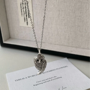 Gros plan du pendentif hibou argenté avec textures de plumes et yeux noirs détaillés