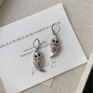 Gros plan de boucles d'oreilles hibou en argent avec pierres noires sur carte artistique