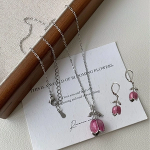 Vue détaillée du collier et des boucles d'oreilles tulipe rose sur fond de carte esthétique