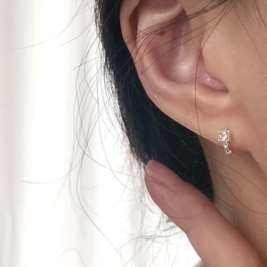Macro shot of silver-toned huggie earrings featuring square champagne zircon stones