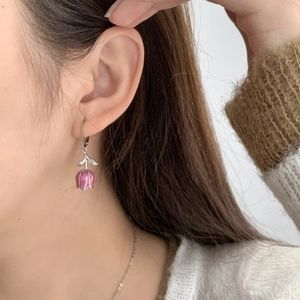 Gros plan de boucles d'oreilles tulipes roses montrant les détails de l'émail sur modèle