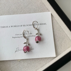 Gros plan sur les boucles d'oreilles tulipes roses avec texture émail sur carte