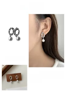 Detailed view of irregular geometric hollow earrings with white pearls in silver finish