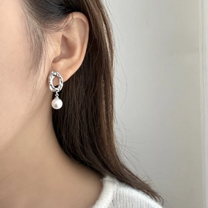 Irregular geometric silver hollow earring with round white pearl on female model