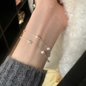 Elegant double-layer star bracelet with frosted beads on a woman wrist, minimalist style
