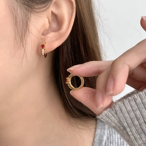 Élégantes boucles d'oreilles en or 18 carats avec pierre rouge ovale et zircons sur modèle