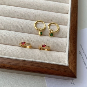 Boucles d'oreilles dorées avec pendentifs verts et pierres rouges ovales sur tissu