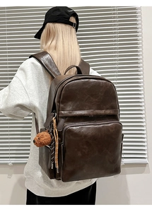 Detail view of large dark brown retro PU leather backpack with plush bear charm accessory