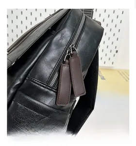 Detail of smooth metal zipper with brown leather puller on black textured PU backpack