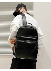 Rear view of man wearing a large black PU leather backpack with a bear pendant detail