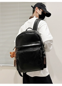 Detail view of black PU leather backpack with a cute brown bear pendant and long pullers