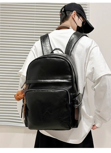 Detailed view of black PU leather backpack featuring a cute brown plush bear charm accessory