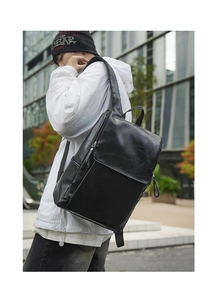 Detail of minimalist black PU leather backpack showing texture and side profile on model