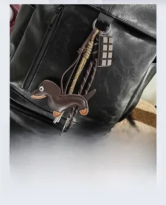 Detail of dachshund leather charm and chocolate pendant on black lychee grain bag
