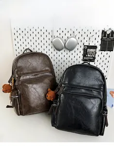 Close-up of vintage PU leather backpacks in brown and black with cute bear charms