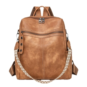 Brown faux leather backpack with textured finish and woven geometric shoulder strap