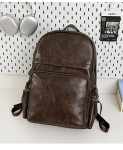 Detail view of a large brown PU leather backpack with a front zipper pocket in a school style