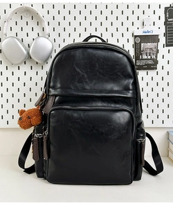 Detail of black PU leather backpack with multi-pocket design and cute bear pendant charm