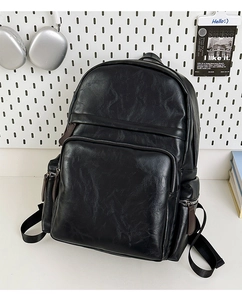 Detail of black PU leather backpack showing vintage texture and front zipper pocket