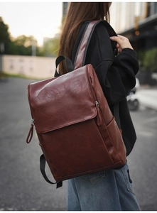 Outdoor shot of a model wearing the brown PU leather backpack with minimalist flap design