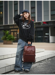 Close-up of a dark brown matte leather backpack styled with street fashion outfit