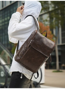 Detail of vintage dark brown PU leather backpack with silver zippers and flap closure
