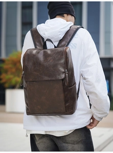 Detailed view of vintage brown leather backpack texture and side pocket design outdoors