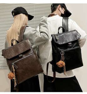 Detail of vintage PU leather backpacks with flap zipper and bear pendant in black and brown