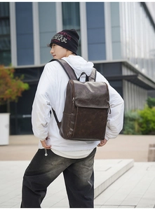 Outdoor shot of a man wearing a vintage dark brown leather backpack with flap closure