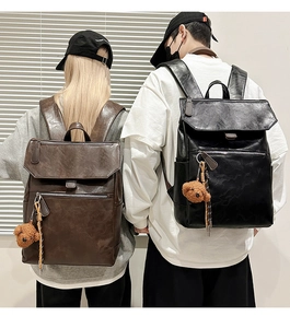 Detail of minimalist leather backpacks in black and brown featuring bear charms and buckles